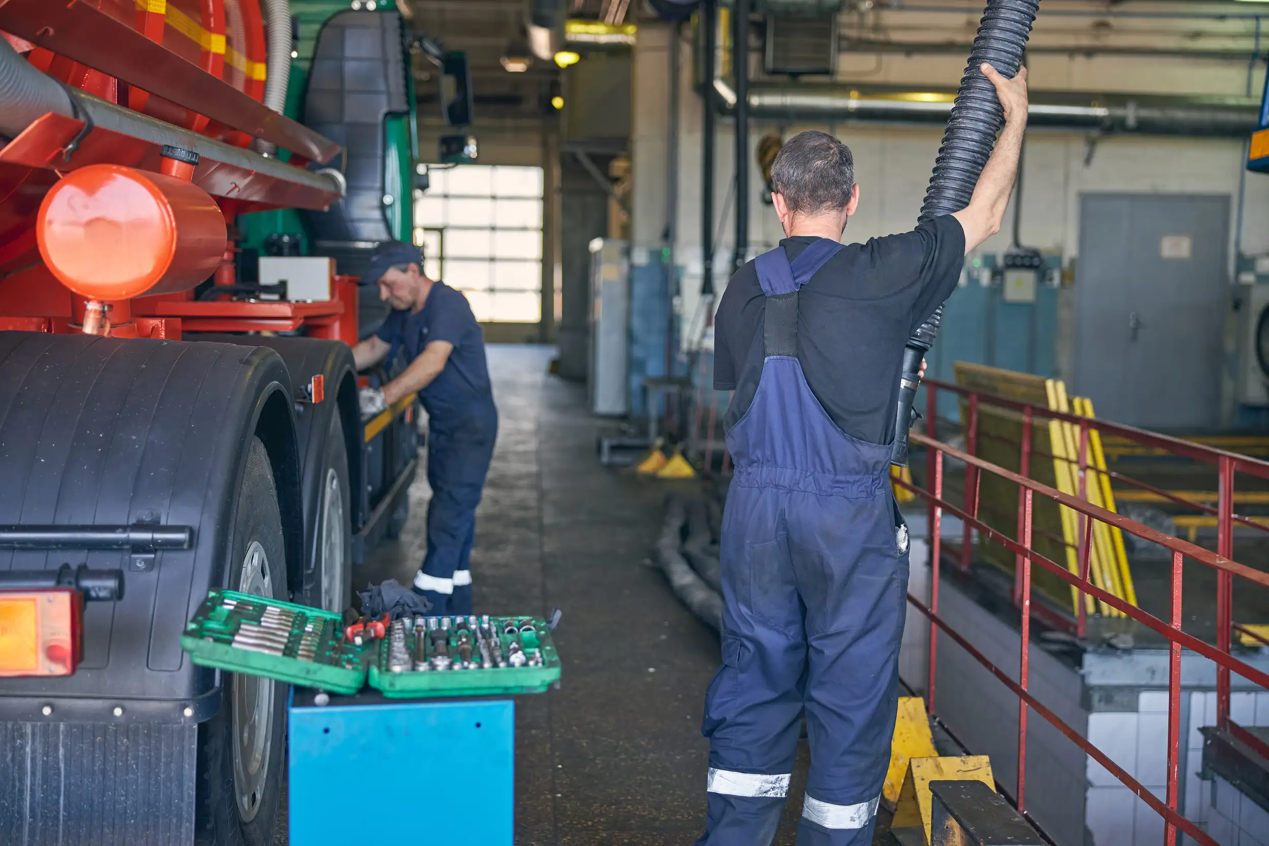 Two male mechanic ensuring the safety and condition of a trailer truck.