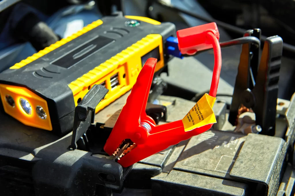 A zoom image of a battery getting jumpstart with cables.