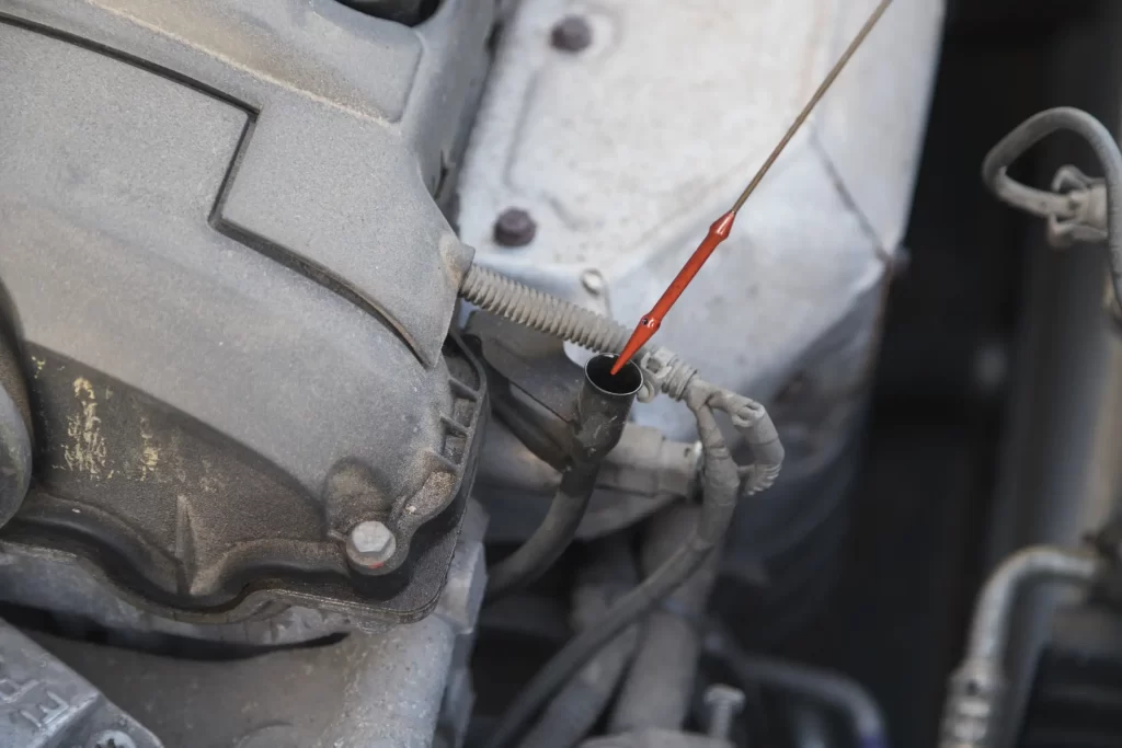 Mechanic examining transmission fluid levels using a dipstick, essential for healthy transmissions.