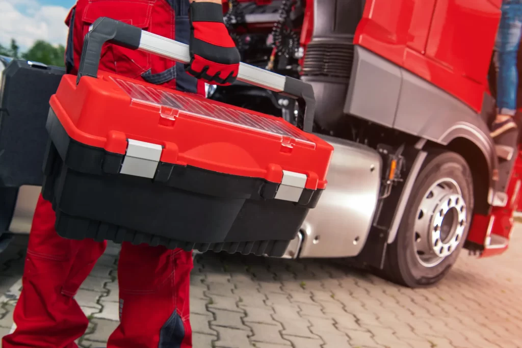 Technician with toolbox ready for truck battery replacement service.