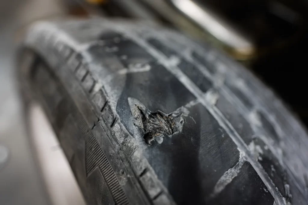 Close-up of a damaged tire requiring immediate tire repair to prevent safety hazards.
