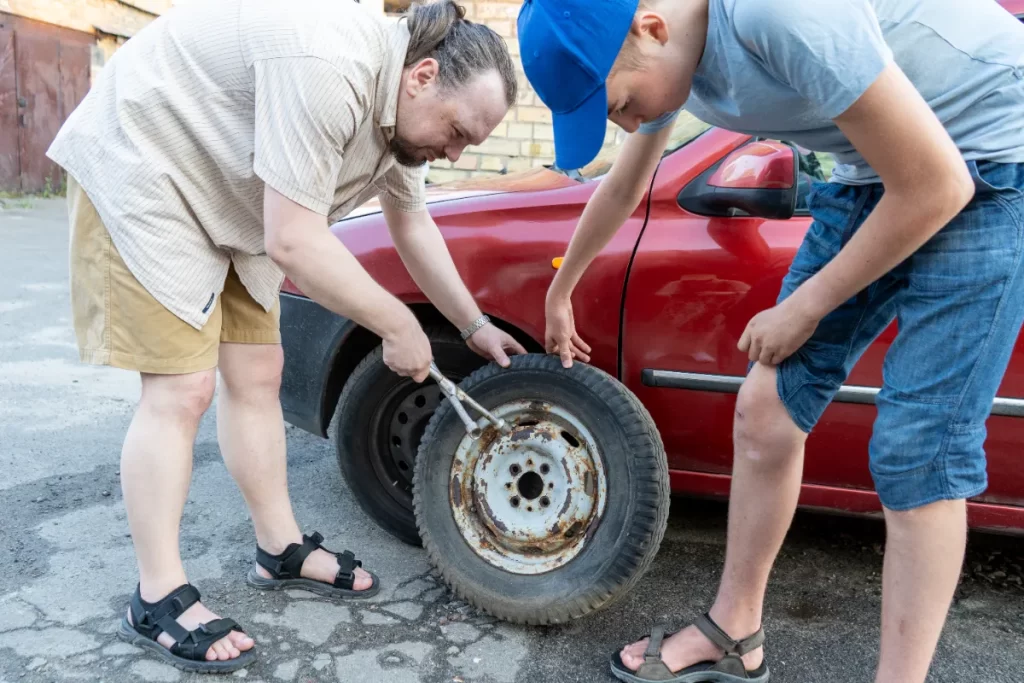 Father and son repairing the tire of their car.