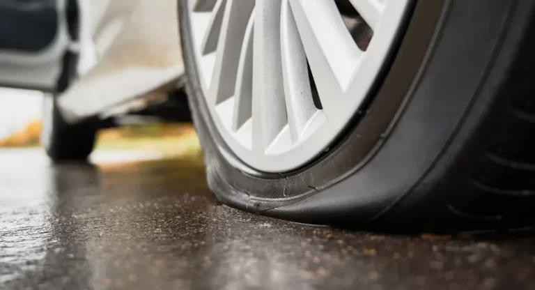 Flat car tire on wet pavement showing damage that may need tire repair.
