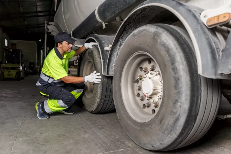 Technician inspecting truck tires after tire repair to ensure safety and performance.