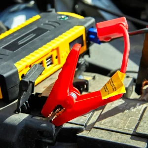 A zoom image of a battery getting jumpstart with cables.