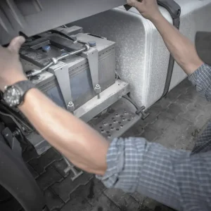 A driver checking the truck's battery.