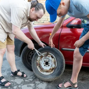 Father and son repairing the tire of their car.