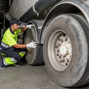 Professional inspecting truck tire for tire repair signs.